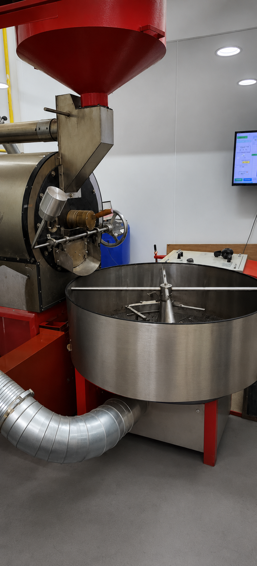 Coffee roasting machine with a red hopper and stainless steel cooling tray.